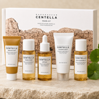 A SKIN1004 Madagascar Centella Travel Kit containing five skincare products arranged on a stone surface in front of their white and brown packaging box.