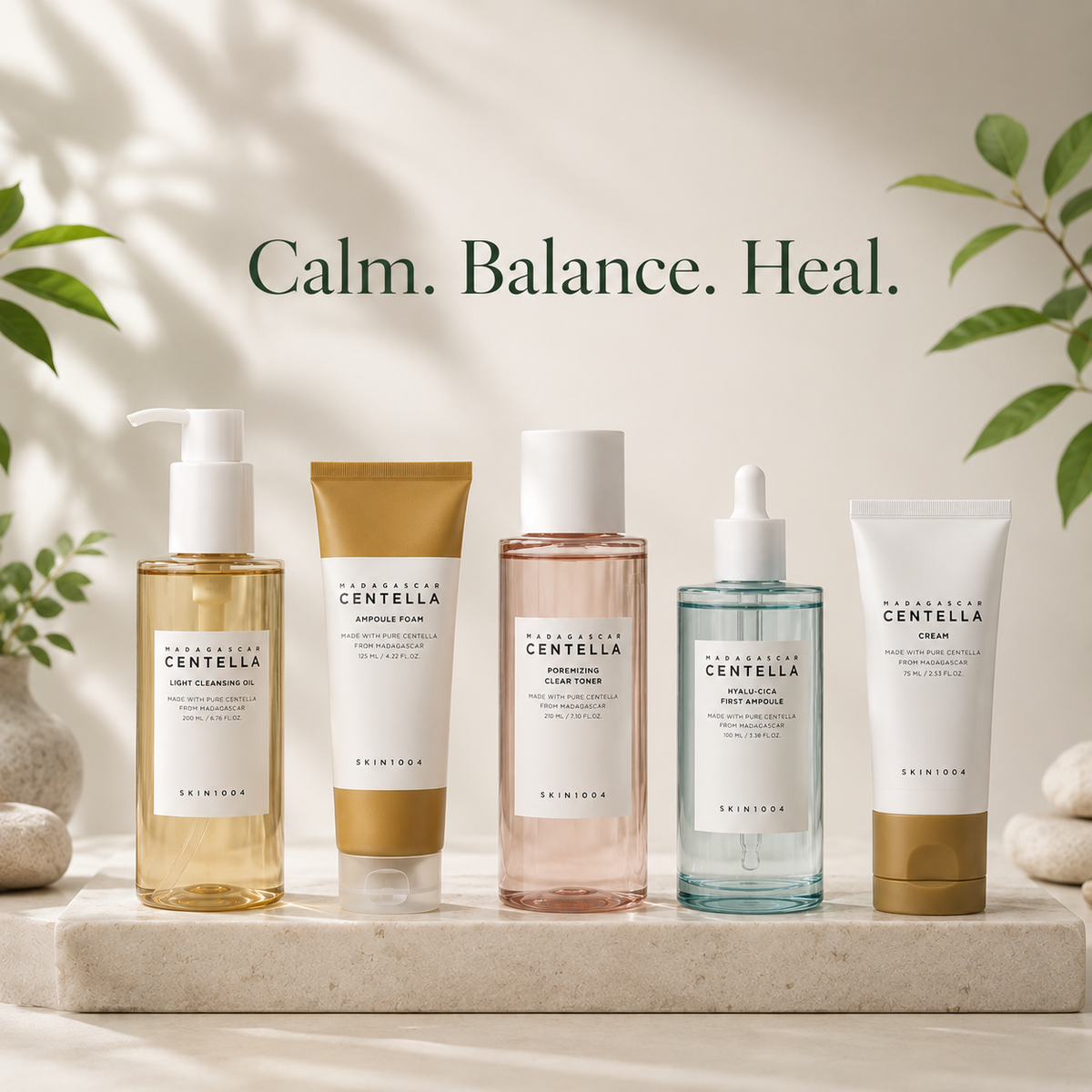 Five skincare products from Dermees Cosmetics are lined up on a light stone slab with a soft beige background, featuring green leaves and shadows. The products include a pump bottle of Cleansing Oil, a squeeze tube of Exfoliating Clay, a pinkish liquid Toner, a dropper bottle of Hydrating Serum, and a cream tube of Repairing Cream.