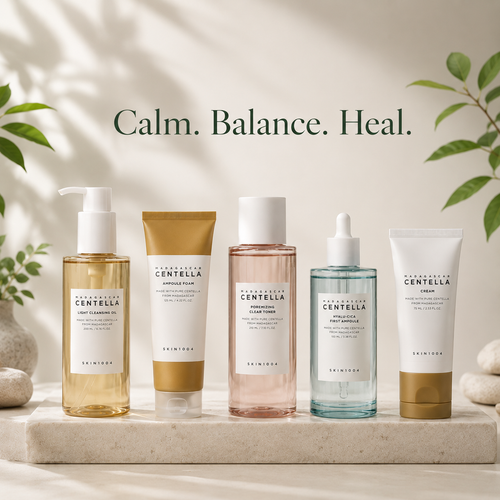 Five skincare products from Dermees Cosmetics are lined up on a light stone slab with a soft beige background, featuring green leaves and shadows. The products include a pump bottle of Cleansing Oil, a squeeze tube of Exfoliating Clay, a pinkish liquid Toner, a dropper bottle of Hydrating Serum, and a cream tube of Repairing Cream.